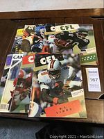 Nine CFL Illustrated magazines spread on a table showing covers with football players and team logos.