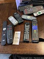 Photo of various remote controls spread out on a table, showing different brands and button configurations.