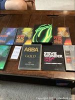 Photo showing assortment of music concert DVDs arranged on wooden table including Rolling Stones, ABBA, Stevie Wonder, and Saturday Night Live DVDs.