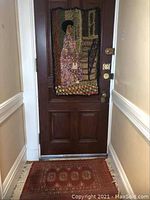 Textile art wall hanging on door depicting woman in red dress by window