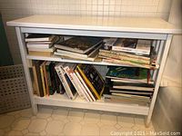 Front view of a white painted wood bookcase filled with books, showing two shelves and a flat top.