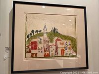 Front view of the framed art print showing the colorful village scene with the church and houses.
