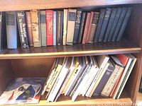 Full view of two bookshelf levels densely packed with hardcover and paperback books of various sizes, predominantly vintage and hardcover.