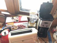 Overview photo of all kitchen appliances including blender, toaster, teapot, and boxed raclette grill