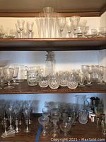 Overview of shelves with assorted glassware including stemware on top shelf, beer mugs and crystal glasses on middle shelf, and assorted glassware on bottom shelf
