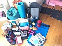 Photo showing all exercise and camping items laid out on hardwood floor including mats, shoes, hand weights, resistance bands, and packaged items.