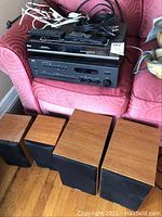 Photo showing all items together: NAD receiver, LG DVD/VHS player, Paradigm speakers, wires, and remotes on a red couch and floor.