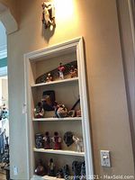 Shelf displaying assorted small folk art figurines and pottery items