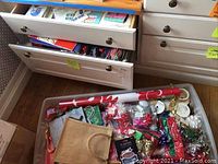 Bin and drawers containing rolls of wrapping paper, ribbons, gift bags, and other supplies