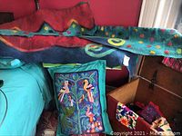 Image showing colorful felted window valances draped over furniture in a red room with a wooden chest and other textiles.