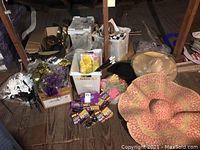 Wide view of boxed and loose party supplies including hats, masks, clappers, and other accessories scattered on wooden floor.