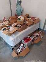 Photo of a table and floor area covered with many boxes of assorted spooled ribbons, including lace and beaded ribbons in various colors