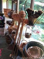 Shelf and floor view of multiple woven and wicker baskets, heart pine sticks and metal wine holders