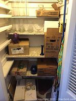 Multiple clear and colored glass vases displayed on shelves inside a closet with boxes, showing some minor damage and dirt.
