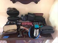 Overall view of various sunglasses, cases and binoculars spread on a wooden surface