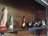 Shelf view of multiple fox figurines, including Herend red and black fishnet patterns and Kaiser dressed fox