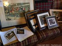 Wide view of the full lot on a couch showing all prints framed and unframed, including a book or album with horse images and terminology pages.