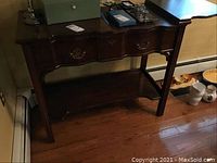 Front view of Harden server showing dark finish, scalloped apron, bottom shelf, slate top with items