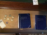 Coins and two blue coin albums arranged on a wooden surface.