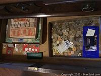 Drawer view showing banknotes at left, loose coins at right, red coin holder, green and blue boxes