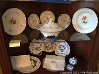 Overview of tureen with lid and floral and blue underglaze plates and jars on shelves