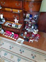 Dresser drawers opened showing assorted boxed and loose Christmas ornaments arranged on drawers and floor.