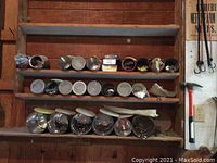 Metal containers with assorted hardware items stored on wooden shelves, some covered.