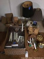 Photo showing two table lamps, various Baldwin Brass electric candle holders and bulbs, and battery-operated candles in cardboard boxes.