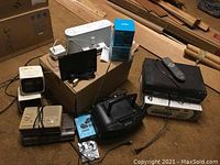 Overview of entire lot showing various electronics on carpet around cardboard box
