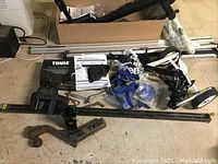 Overview photo of lot laid out on floor showing various racks, bars, hitch and straps in garage