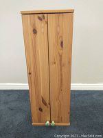 Front view of the small pine shelving unit showing the natural light wood grain and closed double doors.