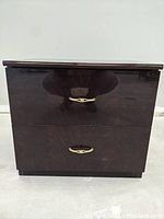 Front view showing two drawer end table in black and maroon lacquer finish with brass handles.