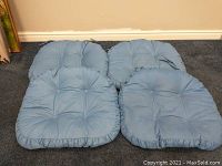 Four blue tufted chair cushions laid on carpet, showing overall condition and styling