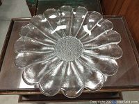 Top view of a clear glass serving bowl shaped like a flower with a textured center and 13 petal-like segments.
