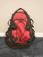 Front view of SwissGear backpack showing red front panel with black sides, bungee cord, and side compression straps.