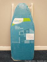 Photo of the ironing board in original sealed packaging, showing brand and basic design.