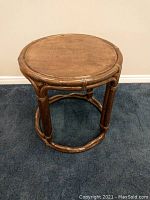 Front angle view of round end table showing leather top with patina and wooden base with circular structure.