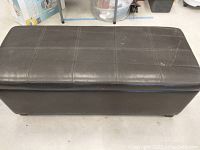 Top view showing rectangular leather seat with stitched square panel design and visible scuffs and wear.