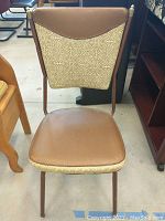 Front view of retro vinyl chair showing the brown vinyl seat and backrest with patterned fabric insert, metal legs and frame.