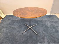 Round dinette table viewed from above, showing the laminated top's brown marbled pattern and smooth edges.