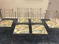 Front view of all six metal-framed chairs with upholstered fruit pattern cushions arranged in two rows.