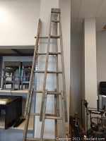 Front view of tall vintage wooden ladder showing 4 pieces stacked to form a folding frame with visible rungs and hinges