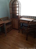 Overview of wicker desk and chair at right, arched wicker bookcase center, small wicker storage unit left