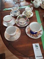 Six assorted decorative teacups and saucers arranged on wooden table