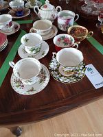 Six teacups and saucers and sugar bowl on wooden table, front view
