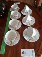 Set of seven Kutani China cups and saucers arranged on a wooden table, showing the overall condition and design.