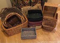 Photo showing a group of woven baskets of different sizes and colors arranged on the floor, including round and rectangular types, stacked and side by side.