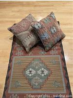 Wool dhurrie carpet runner flat laid with two matching pillows on wood floor, showing colors and geometric patterns