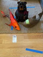 Image showing the wooden fish, paper mache koi fish, and ceramic bear figurines positioned on a carpet with their relative size visible.