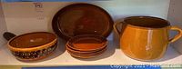 Full view of the stoneware set: large pot, oval dish, small skillet, and 6 plates.